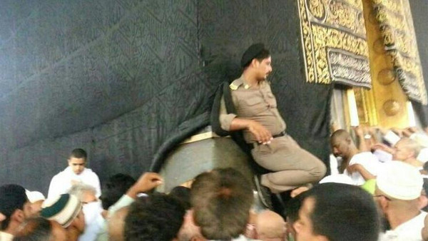 رجل أمني سعودي يضع قدمه على الحجر الأسود الكعبة